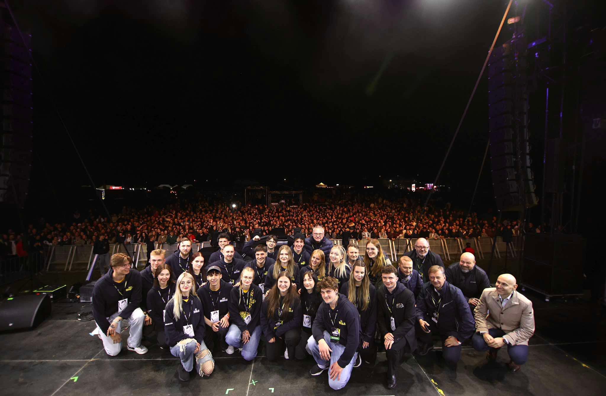 grupa ludzi pozująca do zdjęcia, w tle tłum ludzi, którzy przyszli na koncert