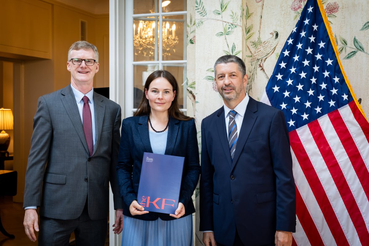 kobieta i dwóch mężczyzn pozujących do zdjęcia na tle tle flagi USA