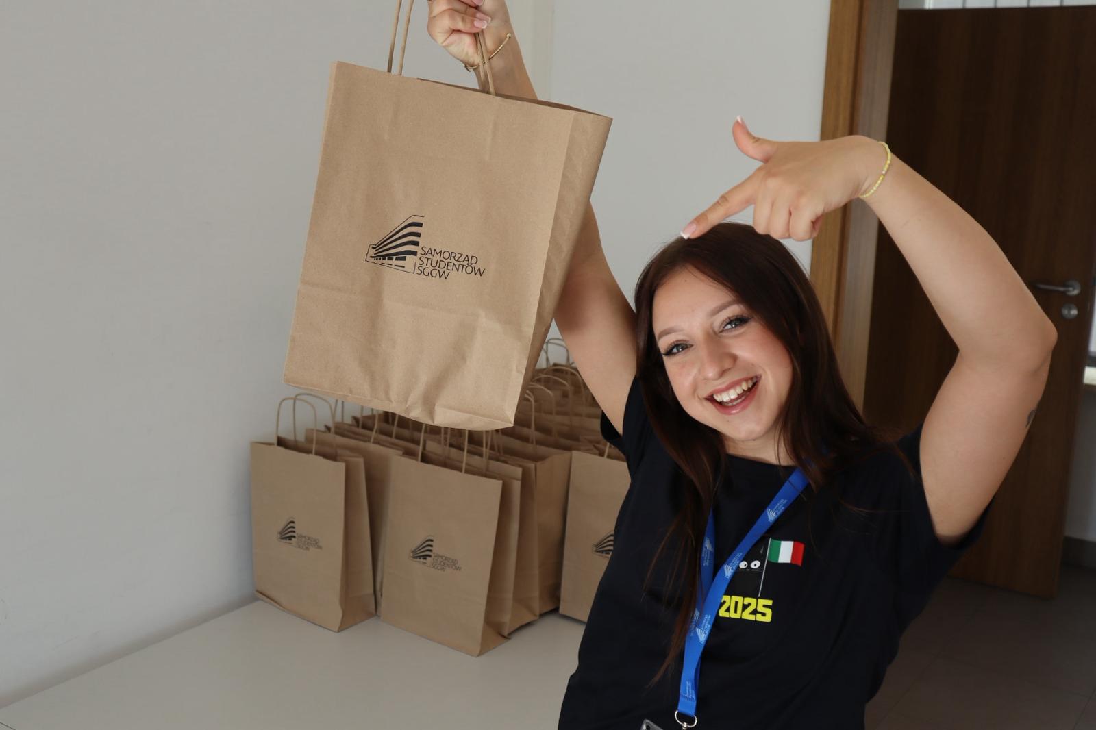 uśmiechnięta studentka trzymająca w ręku papierową torbę z logo Samorządu Studentów SGGW