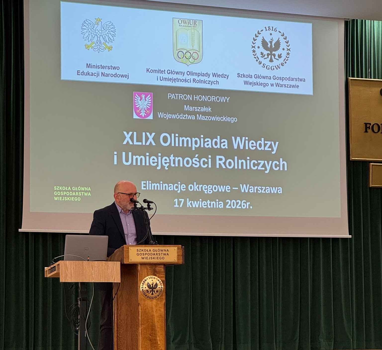 profesor wygłaszający wyniki na mównicy